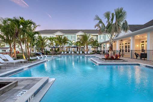A large swimming pool surrounded by palm trees and lounge chairs.
