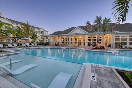 A large swimming pool in front of a building with palm trees.