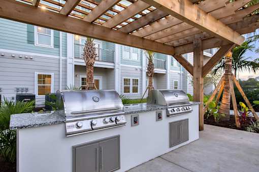A white outdoor kitchen with a grill and sink.