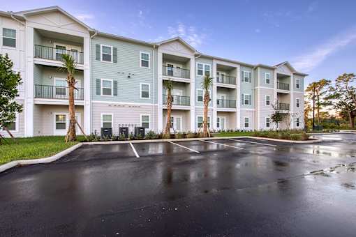 A large apartment complex with a parking lot in front.