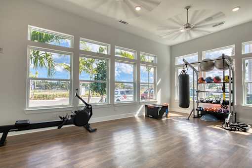 A spacious room with a treadmill, a punching bag, and a rack of exercise equipment.