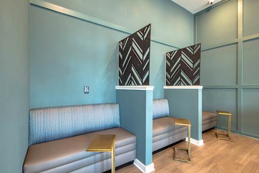 A room with two grey couches and two tables with a black and white patterned tablecloth on top.