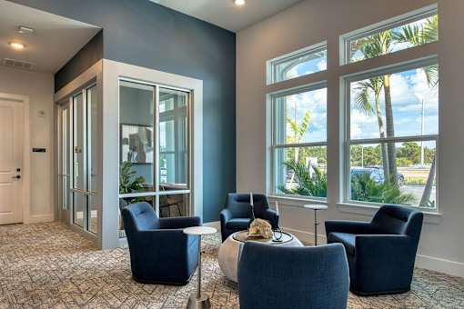 A room with blue chairs and a table with a bowl of food on it.