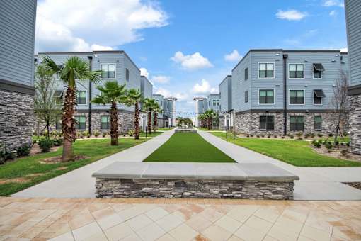 A long walkway with a stone bench in the middle leads to a building.