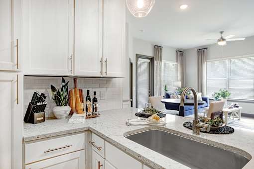 A modern kitchen with white cabinets and a marble countertop.