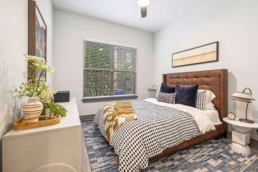 A bedroom with a bed, nightstand, and window.
