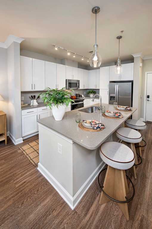 Decatur, GA, Apartments Near Emory University Hospital - Reserve Decatur - Modern Kitchen With Large Island Seating, White Cabinetry, Pendant Lights, and Stainless Steel Appliances.