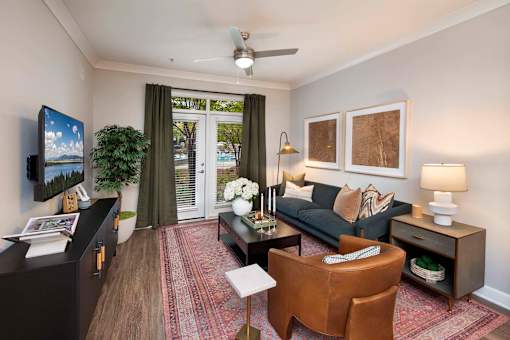 Decatur, GA, Apartments Near Emory University - Reserve Decatur - Inviting Living Room With Couch, Armchair, Designer Plank Flooring, Ceiling Fan, Console Cabinet, Lamps, and French Doors.