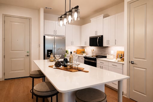 A modern kitchen with a white island and stools.