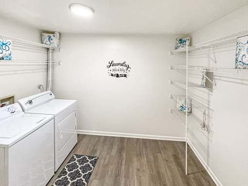 A laundry room with a washer and dryer, a rug, and a wall decal.