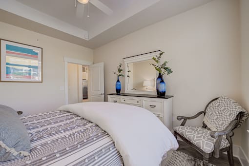 A bedroom with a large bed and a chair.