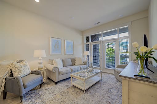 A living room with a grey couch, a white coffee table, and a large window.