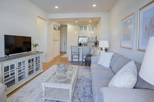 A living room with a grey couch and a glass coffee table.