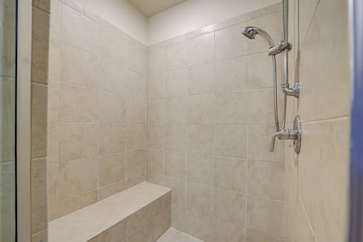A shower area with a bench and a shower head.