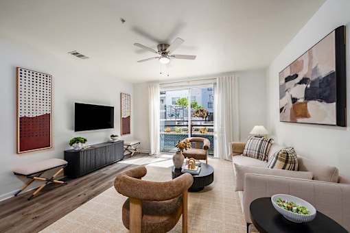 A living room with a television, a chair, a sofa, and a table with a bowl of salad on it.