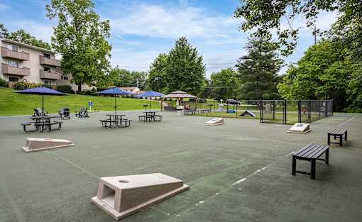 A park with a basketball court, picnic tables, and umbrellas.