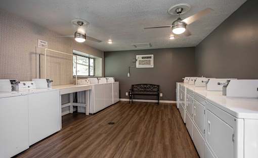A laundry room with a washer and dryer on the left and a bench in the middle.