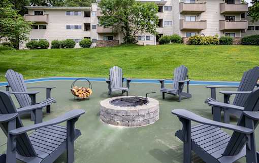 A fire pit surrounded by chairs in a backyard.
