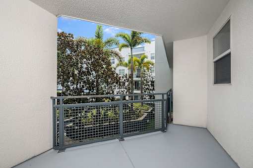 A balcony with a metal railing overlooking a lush green area.