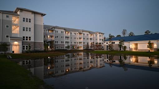 Apartment buildings are reflected in the water in front of them.