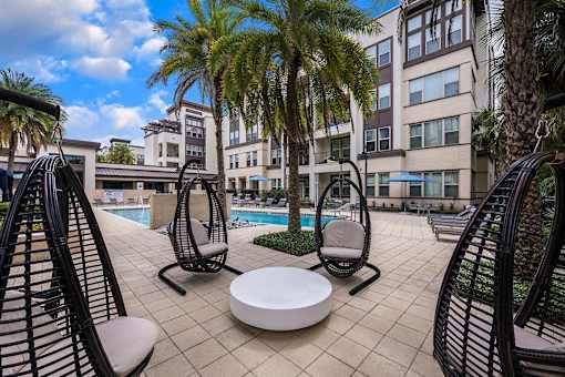 A patio with a table and chairs overlooking a pool.
