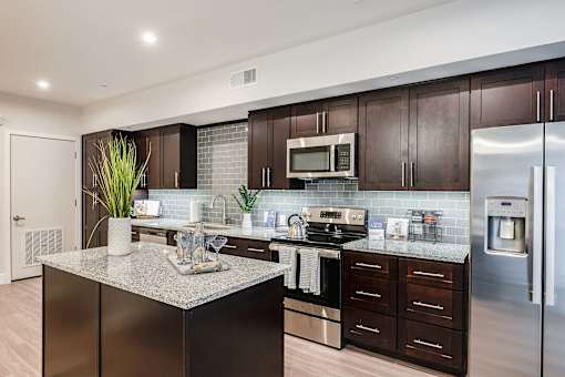 A modern kitchen with dark wood cabinets and stainless steel appliances.