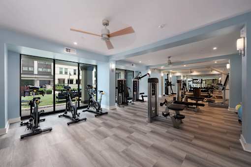 A spacious gym with a variety of exercise equipment and a view of the outside.
