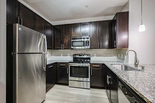A kitchen with a stainless steel refrigerator and black cabinets.