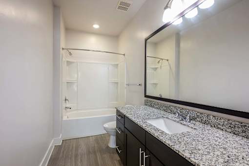 A bathroom with a white tub, sink, and mirror.
