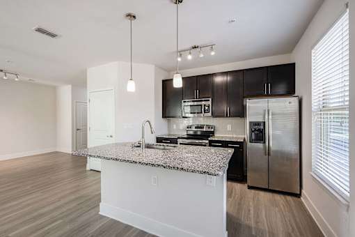 A modern kitchen with a granite countertop and stainless steel appliances.