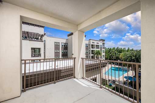 A balcony with a pool and buildings in the background.