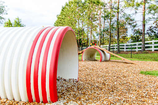 A red and white striped tunnel sits in a field of gravel.