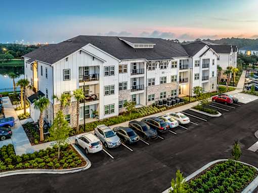 A parking lot in front of a white apartment building.