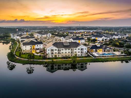 A serene landscape with a building reflected in a body of water during sunset.