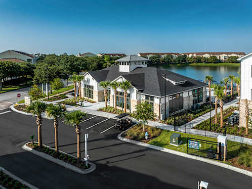 A large building with a black roof is surrounded by a parking lot and palm trees.