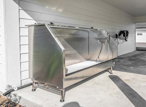 A large metal container with wheels and a handle is placed on a concrete floor.