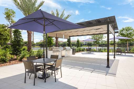 A patio with a table and chairs under a purple umbrella.
