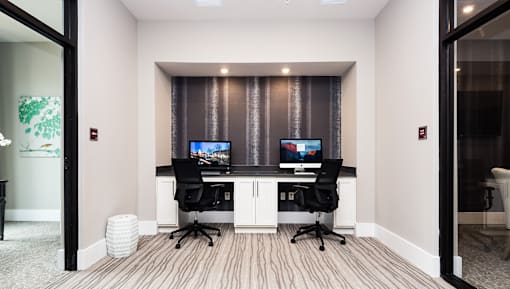 A room with two computer desks and chairs.