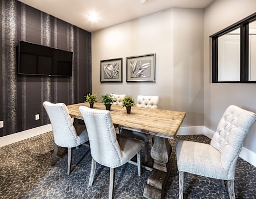 A dining room with a wooden table and white chairs.