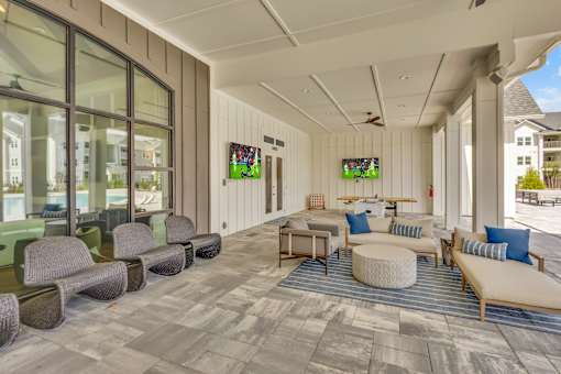 A spacious room with a long couch and a round ottoman in the center.