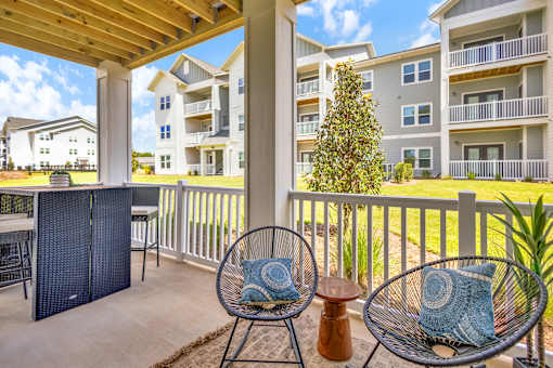 A patio with a chair and a table with a blue pillow on it.