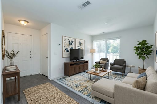 A living room with a couch, chairs, and a television.