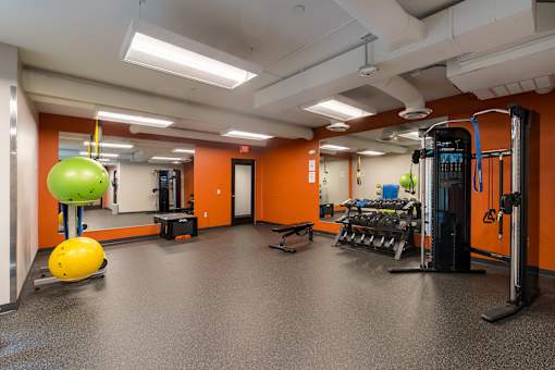 A gym with orange walls and a variety of equipment.