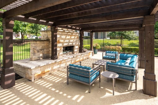 a covered patio with a stone fireplace and blue couches at Orion McCord Park, Little Elm, TX, 75068
