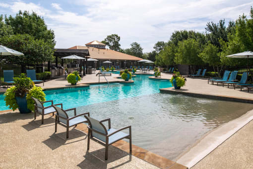 a swimming pool with chairs and umbrellas at Orion McCord Park, Little Elm, TX, 75068