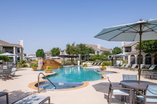 a swimming pool with patio furniture and umbrellas in front of a resort style at Orion Prosper Lakes, Prosper, TX, 75078