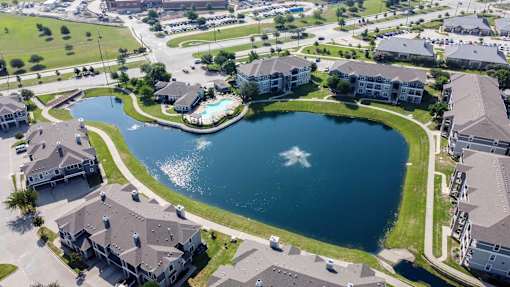 A bird's eye view of a residential area with a lake in the middle.