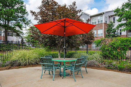 A red umbrella is in front of a green table.