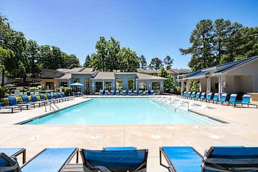 A large swimming pool surrounded by lounge chairs and trees.