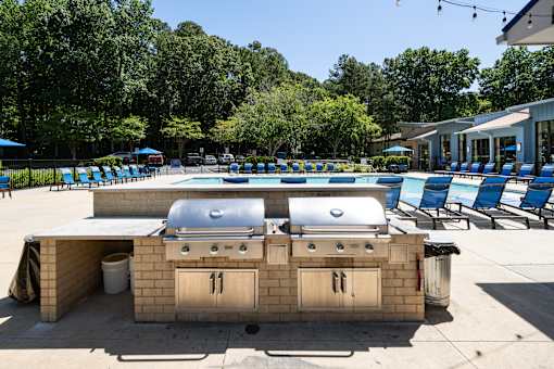 A barbecue grill is in the middle of a pool area.